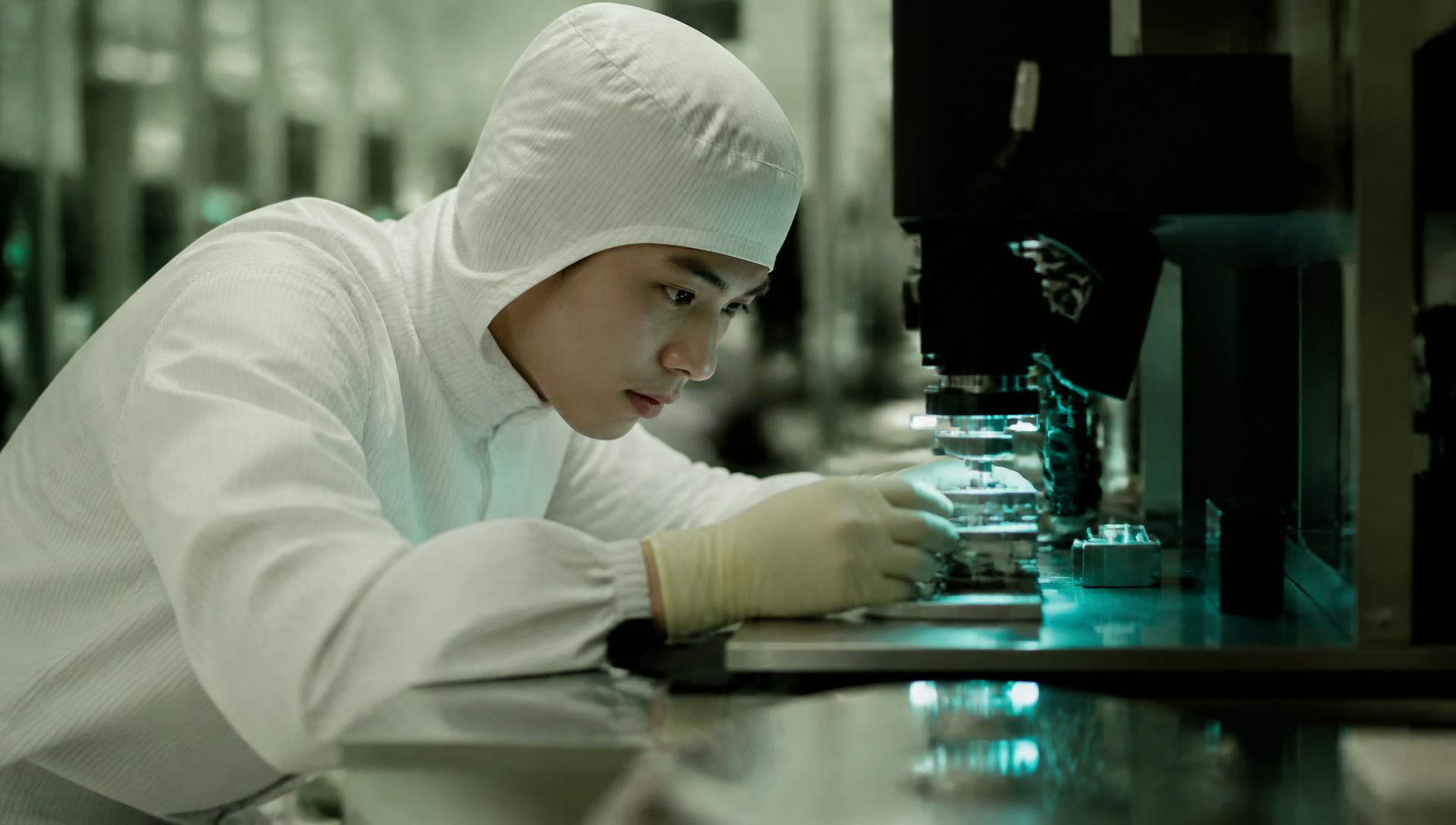 Technicien de salle blanche réglant un équipement de métrologie sur une ligne de microélectronique du CEA-Leti, lumière turquoise.